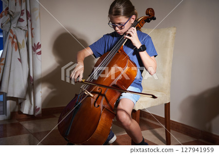 Young Musician Practicing Cello at Home in a Comfortable Setting Using Proper Technique Young Musician Practicing Cello at Home in a Comfortable Setting Using Proper Technique 127941959