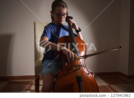 Young Girl Playing Cello in a Warmly Lit Room Demonstrating Musical Talent Young Girl Playing Cello in a Warmly Lit Room Demonstrating Musical Talent 127941962