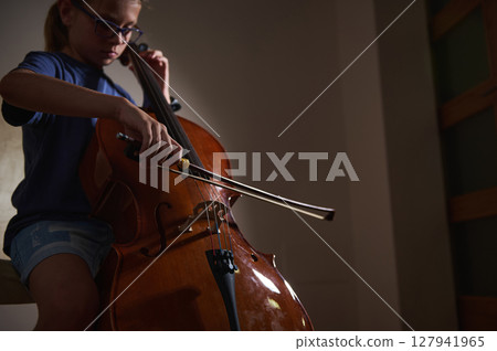 Young Musician Playing the Cello in a Dimly Lit Room Young Musician Playing the Cello in a Dimly Lit Room 127941965