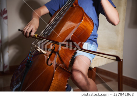 Close-Up of a Young Musician Playing a Cello in a Warm Indoors Setting 127941968