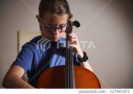 Young Girl Concentrating While Playing the Cello in a Focused Setting 127941971