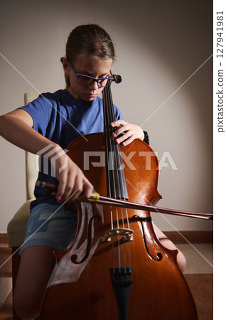 Young Girl Practicing Cello with Focus and Determination in a Minimalist Room 127941981