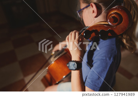 Close-Up of a Young Musician Playing the Cello in a Sunlit Room 127941989