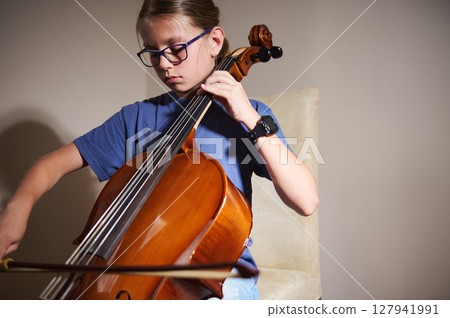 Young Girl Playing the Cello Enthusiastically in a Well-Lit Room Young Girl Playing the Cello Enthusiastically in a Well-Lit Room 127941991