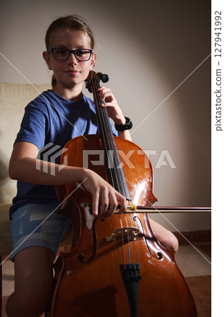 Young Musician Practicing the Cello in a Serene Setting 127941992