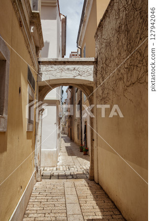Narrow stone alley with arch. Old European town Porec, Croatia. 127942046