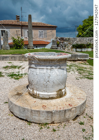 Ancient stone well with Roman columns archaeological site. Porec, Croatia 127942047