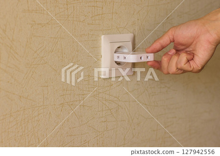 Manually plugging an electrical device into a wall outlet for convenient use and power Manually plugging an electrical device into a wall outlet for convenient use and power 127942556