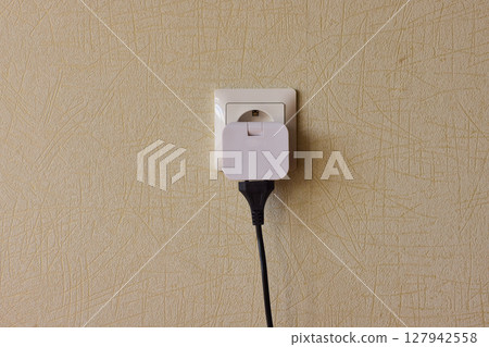 Manually plugging an electrical device into a wall outlet for convenient use and power Manually plugging an electrical device into a wall outlet for convenient use and power 127942558