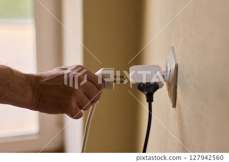 Manually plugging an electrical device into a wall outlet for convenient use and power Manually plugging an electrical device into a wall outlet for convenient use and power 127942560