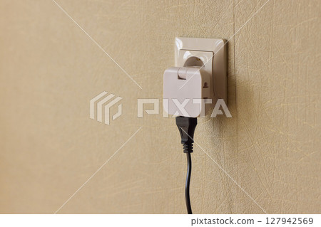 Manually plugging an electrical device into a wall outlet for convenient use and power 127942569