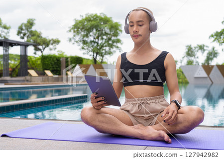 Non-binary person exercising in poolside doing yoga and wearing sport bra 127942982