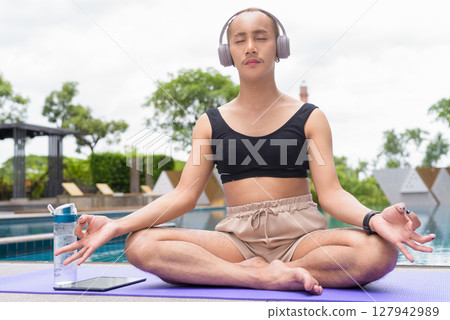 Non-binary person exercising in poolside doing yoga and wearing sport bra 127942989