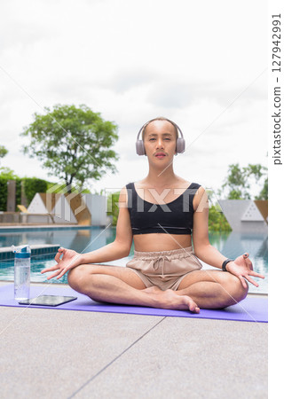 Non-binary person exercising in poolside doing yoga and wearing sport bra Non-binary person exercising in poolside doing yoga and wearing sport bra 127942991