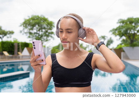Non-binary person exercising in poolside doing yoga and wearing sport bra 127943000