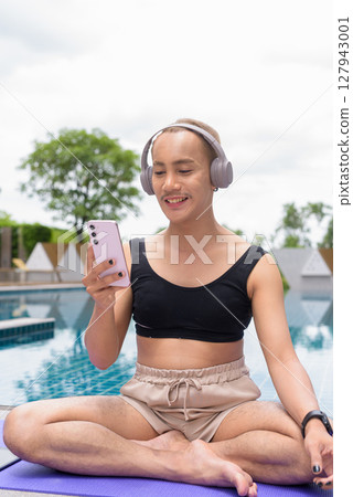 Non-binary person exercising in poolside doing yoga and wearing sport bra 127943001