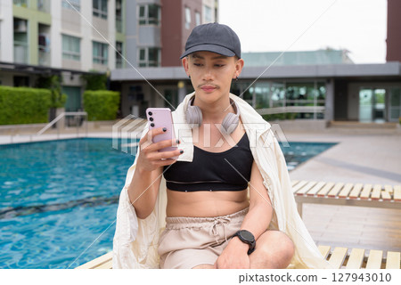 Non-binary person relaxing in poolside during summer wearing sport bra Non-binary person relaxing in poolside during summer wearing sport bra 127943010