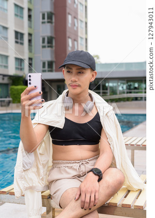 Non-binary person relaxing in poolside during summer wearing sport bra Non-binary person relaxing in poolside during summer wearing sport bra 127943011