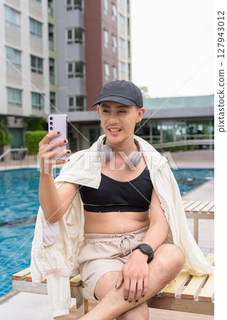 Non-binary person relaxing in poolside during summer wearing sport bra Non-binary person relaxing in poolside during summer wearing sport bra 127943012