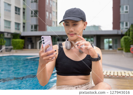 Non-binary person relaxing in poolside during summer wearing sport bra Non-binary person relaxing in poolside during summer wearing sport bra 127943016