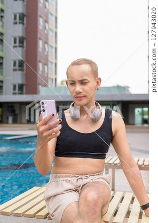 Non-binary person relaxing in poolside during summer wearing sport bra Non-binary person relaxing in poolside during summer wearing sport bra 127943020
