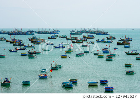 Fleet of Fishing and Basket Boats Float Peacefully on the Turquoise Waters of Mui Ne Bay, Vietnam 127943627