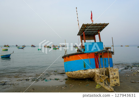 Colorful Fishing Boat Beached at Dawn in Mui Ne with Fleet in the Background 127943631