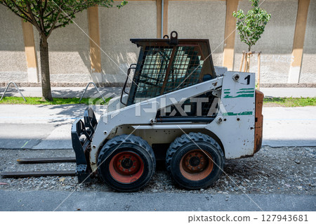 Small skid steer loader on road construction site in city Small skid steer loader on road construction site in city 127943681