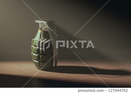 Hand grenade on a dark wooden floor illuminated by ray of the light 127944702
