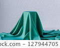 Cubic pedestal covered by green soft fabric 127944705