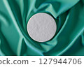 White object is placed on a green fabric 127944706