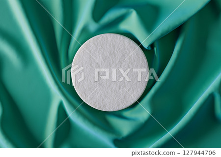 White object is placed on a green fabric 127944706