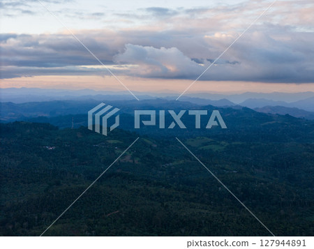 Mountainous landscape view under cloudy sky at dusk near rural area 127944891