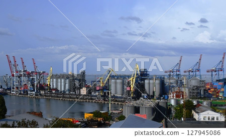 Port landscape with cargo loaders and grain elevators under blue sky 127945086