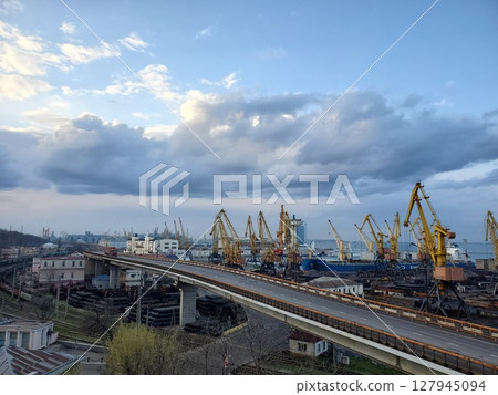 Industrial port landscape with cargo trucks driving by overpass Industrial port landscape with cargo trucks driving by overpass 127945094