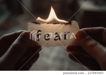 Hands holding burning paper with fear written on it 127945497