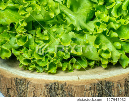 Bunch of lettuce on a wooden tray. Salad concept. Vitamin of natural origin. Leaves up close. Grass background for food. Useful ingredient. 127945982