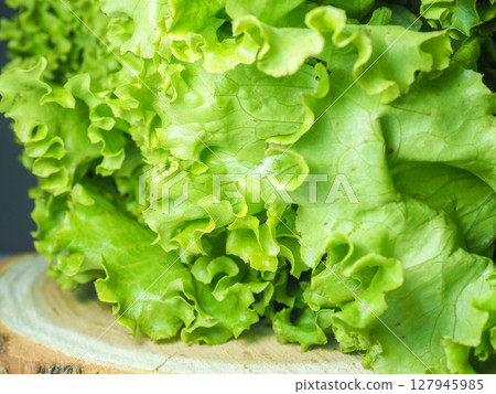Bunch of lettuce on a wooden tray. Salad concept. Vitamin of natural origin. Leaves up close. Grass background for food. Useful ingredient. Bunch of lettuce on a wooden tray. Salad concept. Vitamin of natural origin. Leaves up close. Grass background for food. Useful ingredient. 127945985