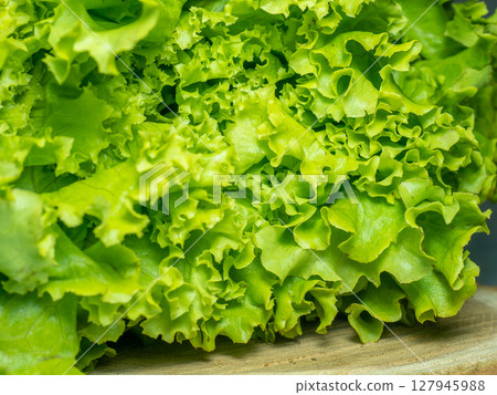 Bunch of lettuce on a wooden tray. Salad concept. Vitamin of natural origin. Leaves up close. Grass background for food. Useful ingredient. 127945988