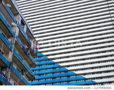 Modern building and old building. Contrast of houses. New and old. Tall building. Lots of windows. Skyscraper, floors. Human anthill. Modern hostel. 127946000