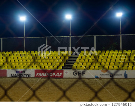 Beach soccer field through the fence mesh. Sand play concept. Competition sponsors. View of the viewer. Team Confrontation Beach soccer field through the fence mesh. Sand play concept. Competition sponsors. View of the viewer. Team Confrontation 127946015