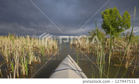 paddling under stormy sky through narrow passage in reeds- POV view from paddling kayak or canoe on Boedecker Reservoir in Loveland, Colorado paddling under stormy sky through narrow passage in reeds- POV view from paddling kayak or canoe on Boedecker Reservoir in Loveland, Colorado 127947511