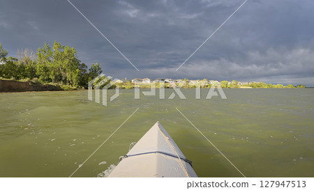paddling under stormy sky - POV view from paddling kayak or canoe on Boedecker Reservoir in Loveland, Colorado paddling under stormy sky - POV view from paddling kayak or canoe on Boedecker Reservoir in Loveland, Colorado 127947513