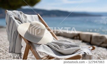 Relaxing beach setting with a straw hat and soft blanket by the shore 127947863