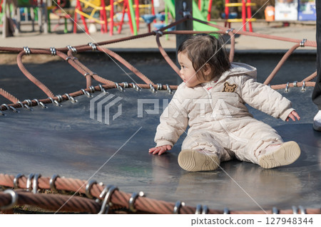 [A one-year-old child playing with his mother on the trampoline in the children's playground at Sagamihara City Asamizo Park] 127948344