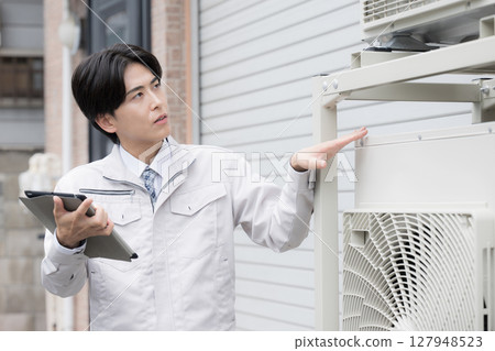 A worker inspecting an outdoor unit points to check for safety A worker inspecting an outdoor unit points to check for safety 127948523