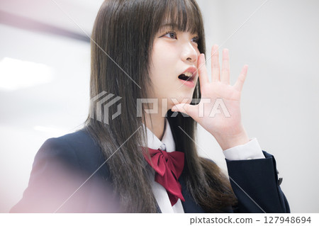 特寫：在學校或補習班上微笑的高中女生，為通過考試歡呼雀躍，前面是模糊的櫻花 127948694