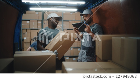 Employees Unloading Delivery Truck with Cardboard Boxes. Manager Scanning Parcels Using Digital Tablet 127949368