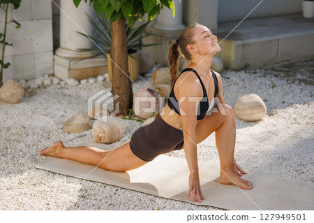 Woman stretching in yoga pilates pose outdoors on mat flexibility fitness wellness and healthy lifestyle routine. Woman stretching in yoga pilates pose outdoors on mat flexibility fitness wellness and healthy lifestyle routine. 127949501