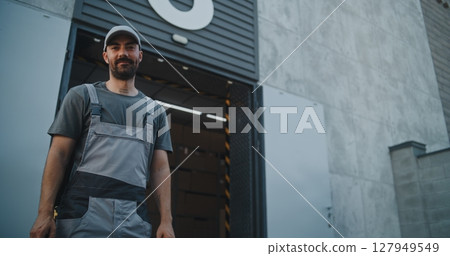 Worker Giving Cardboard Box to African American Colleague for Delivery, Looking at Camera Worker Giving Cardboard Box to African American Colleague for Delivery, Looking at Camera 127949549
